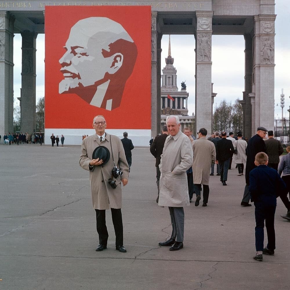 Иностранные туристы фотографируются с портретом Ленина у главного входа ВДНХ.
