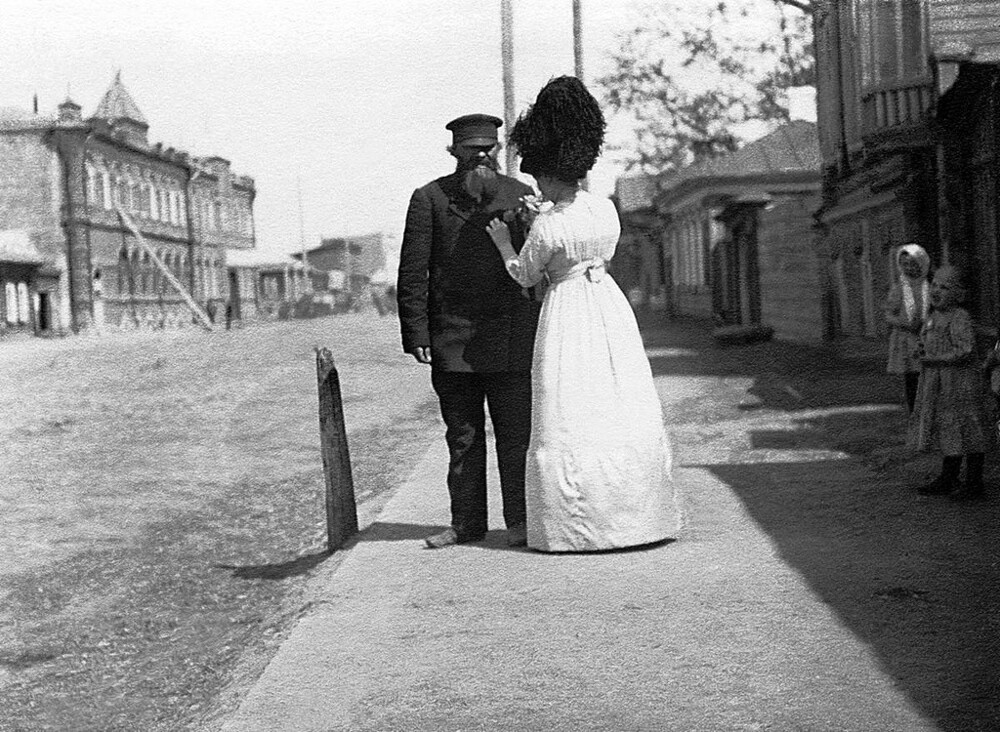 Дама прикалывает значок участника праздника одному из горожан. Из фотоальбома «Праздник "День колоса"». 1912 год. Дама прикалывает значок участника праздника одному из горожан. Из фотоальбома «Праздник "День колоса"». 1912 год.