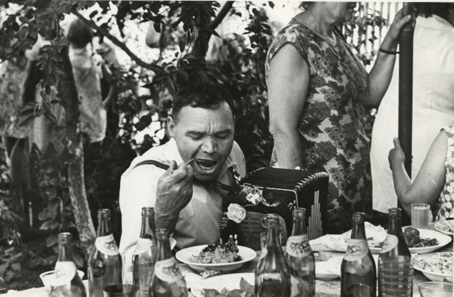 «Не следует стараться есть в гостях мало. Ешьте в меру своего аппетита». Фото: Гармонист. 1970-е. Автор: Юрий Рыбчинский.