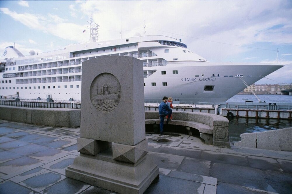 Памятная стела крейсеру "Аврора" на набережной Красного Флота на фоне круизного лайнера "Silver Cloud".
