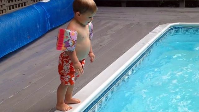 Пытаясь научится прыгать, как мама, маленький мальчик забавно плюхнулся в бассейн