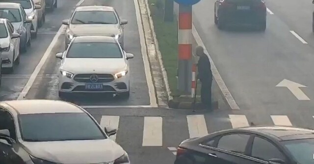 Пожилой китаец с тростью переходит многополосную дорогу