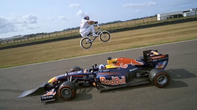 Прыжок на велосипеде BMX через машину Формулы-1