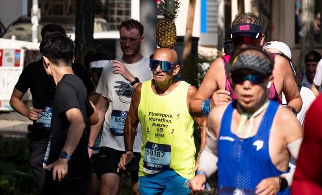 Пожилой мужчина бегает марафоны, удерживая ананас на голове