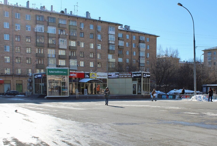 В центре кадра сохранилась с советских времён временная постройка, в которой изначально было кафе, теперь там разные магазины и несколько  кафе